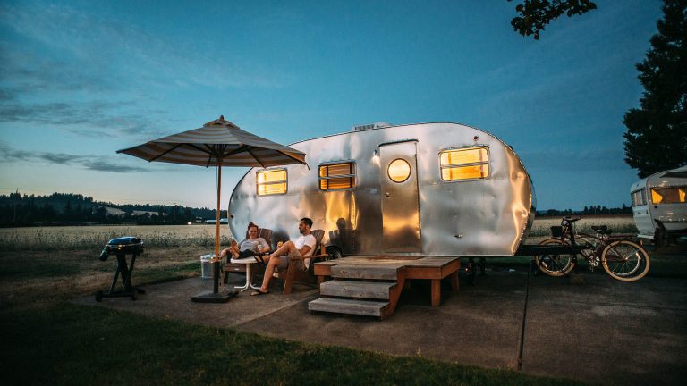 Bild eines Paars vor einem Campingwagen Camping 2025 Reisekompass